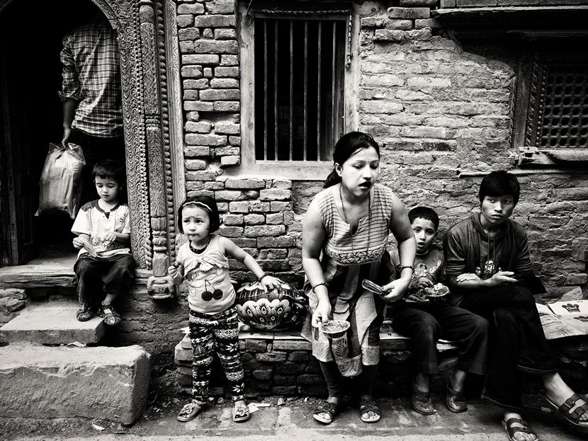 Alcune persone sedute accanto ad un venditore di cibo Persone panchina Nepal