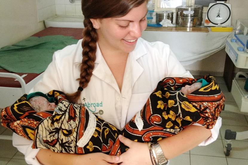 Een vrijwilliger in Tanzania heeft een pasgeboren tweeling in haar armen op het verloskunde project Vrijwilliger Tanzania verloskunde project