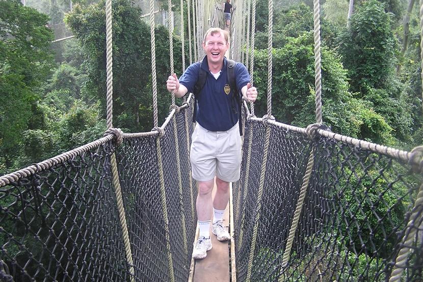 A man walks along a canopy platform in Kakum National Park A man walking a canopy platform
