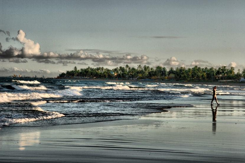 A person walking along the shore Waves breaking on the sand