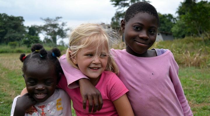 Volunteering as a family in Ghana on a Care project The daughter of a Dutch family on a Care volunteering trip poses with her new friends