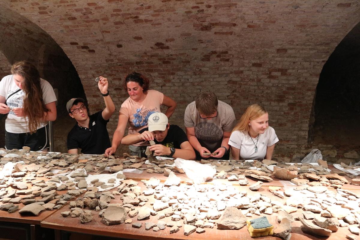 A group of Archaeology volunteers examine ceramics dug up at an excavation site in Romania. Archaeology volunteers in Romania look at the ceramic artefacts uncovered at their dig site in Eastern Europe.