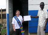 Suzi Lamb receiving a certificate from Alex Adjanie outside her classroom
