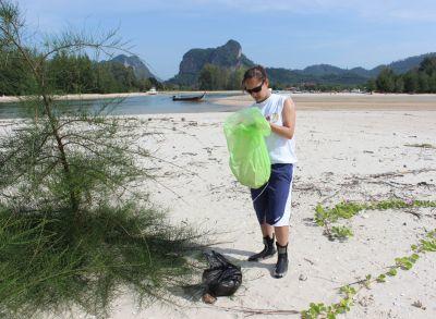 A volunteer fills up a rubbish bag while beach cleaning in Thailand Removing debris from the beach is key to oceanic health
