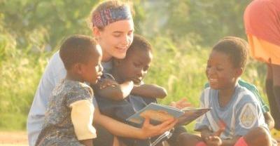 A volunteer reads to a group of young children during the 'Football Pitch Reading' in Ghana Children get read to by a volunteer