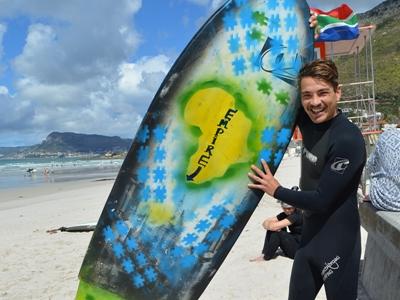Ashtan Davids' surfing coach with his adapted board Surfing manager Chrisjan holds Ashtan's surfing board