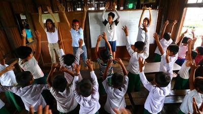 Volunteers teach students in a classroom Volunteers work with children