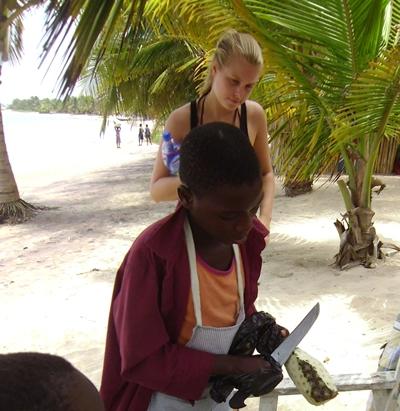Ein Mädchen, das mit ihrem kleinen Bruder frische Ananas am Strand an Touristen verkauft ghana-menschenrechte-ananas