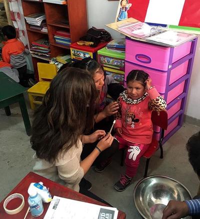 Volunteer gives a child flouride during a medical outreach Volunteer
