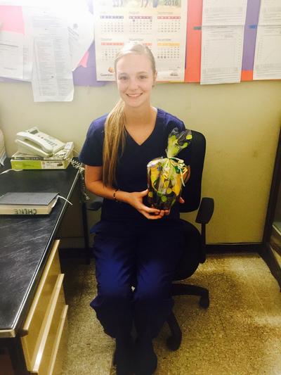 Sydney P. in her scrubs with a gift from a patient Sydney P. in her scrubs with a gift from a patient