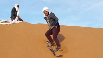 Un volontaire sur une planche de snowboard dans le désert marocain Un volontaire sur une planche de snowboard dans le désert marocain