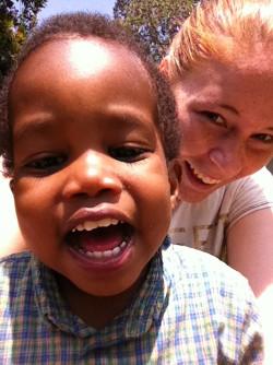 Frivillig Daniella med smilende barn i Tanzania Frivillige Daniella smiler sammen med barn i Tanzania.